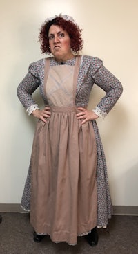 a woman in a dress and apron posing for a photo